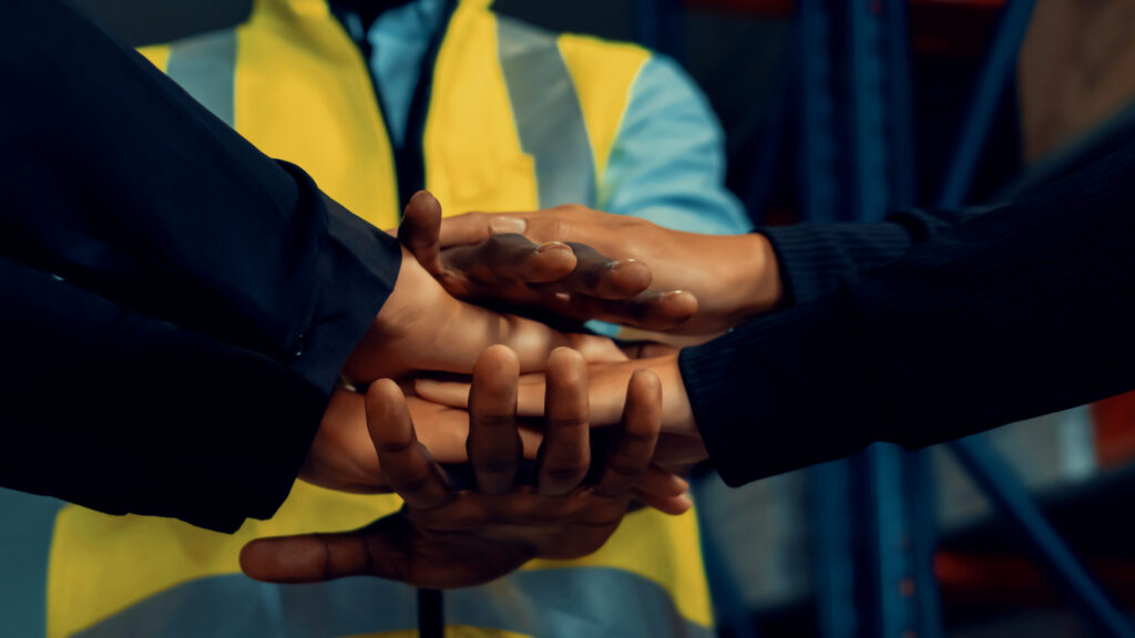 Workers stacking hands in a show of teamwork.